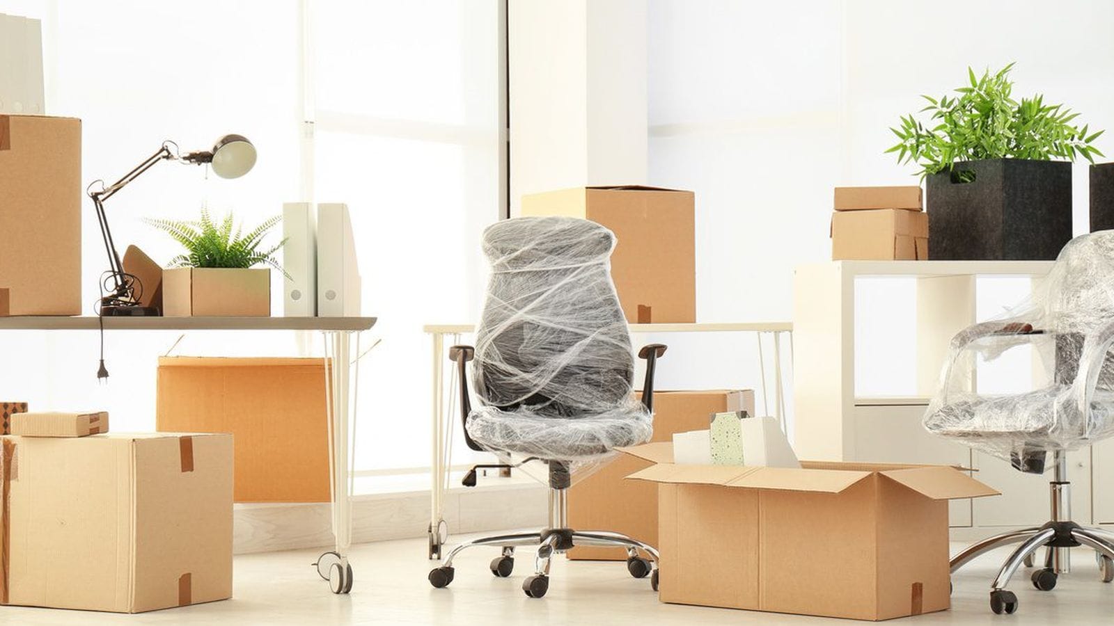 Cardboard boxes and shrink-wrapped office chairs staged during a workspace move