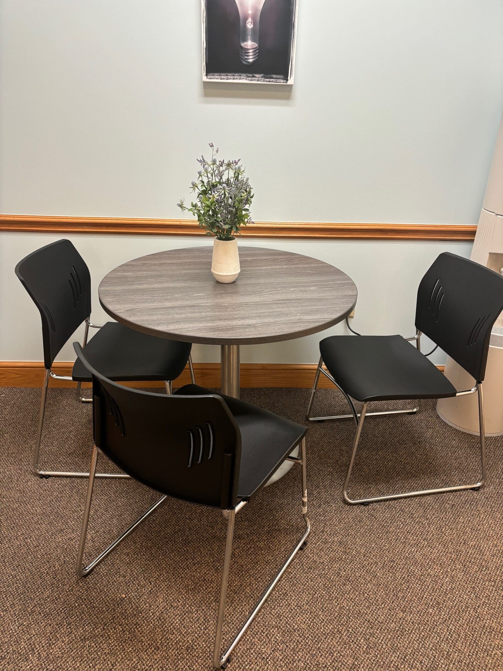 Grey meeting table with black sled base chairs around it